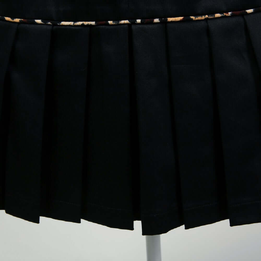 Close-up of a black pencil skirt featuring elegant pleats and leopard piping for a sophisticated look.