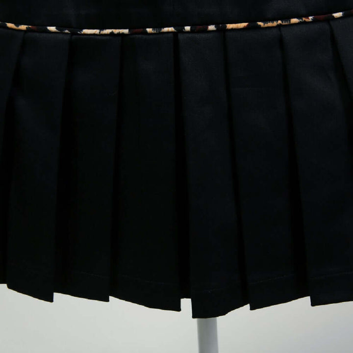 Close-up of a black pencil skirt featuring elegant pleats and leopard piping for a sophisticated look.