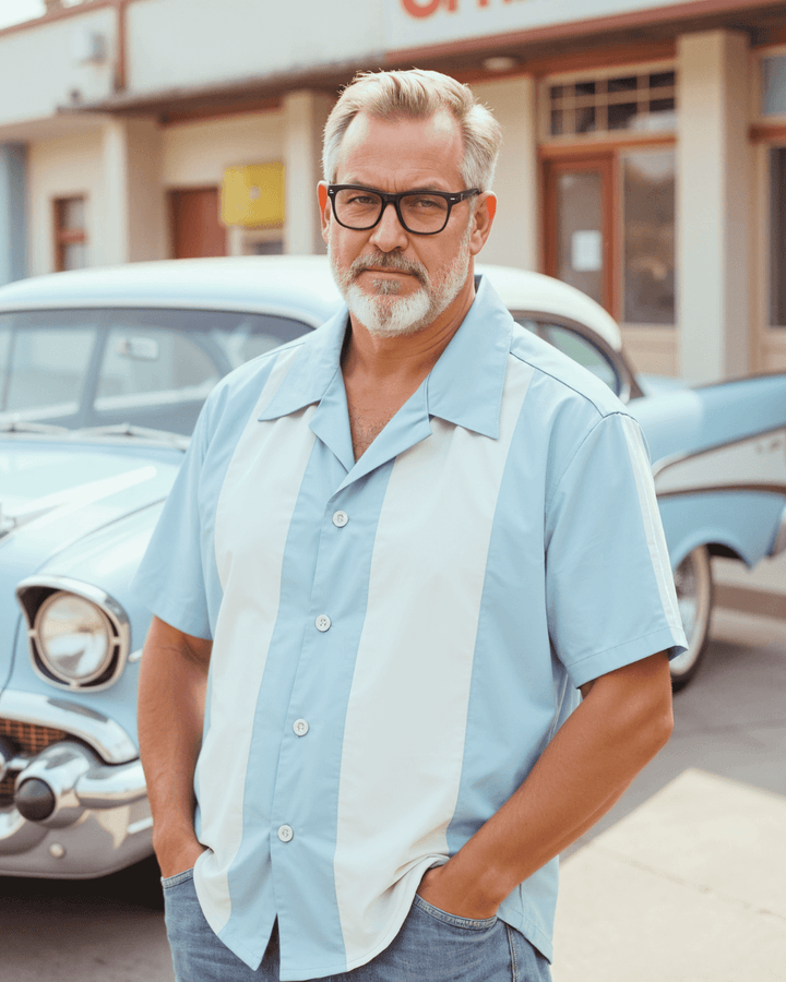 Man wearing a vintage pale blue and white panel bowling shirt, standing in front of a classic car.