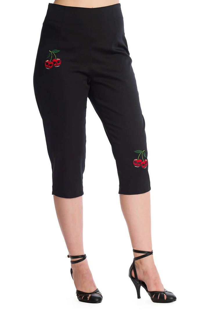 High-waisted black pedal pushers with cherry skull embroidery, styled with strappy heels for a rockabilly look.
