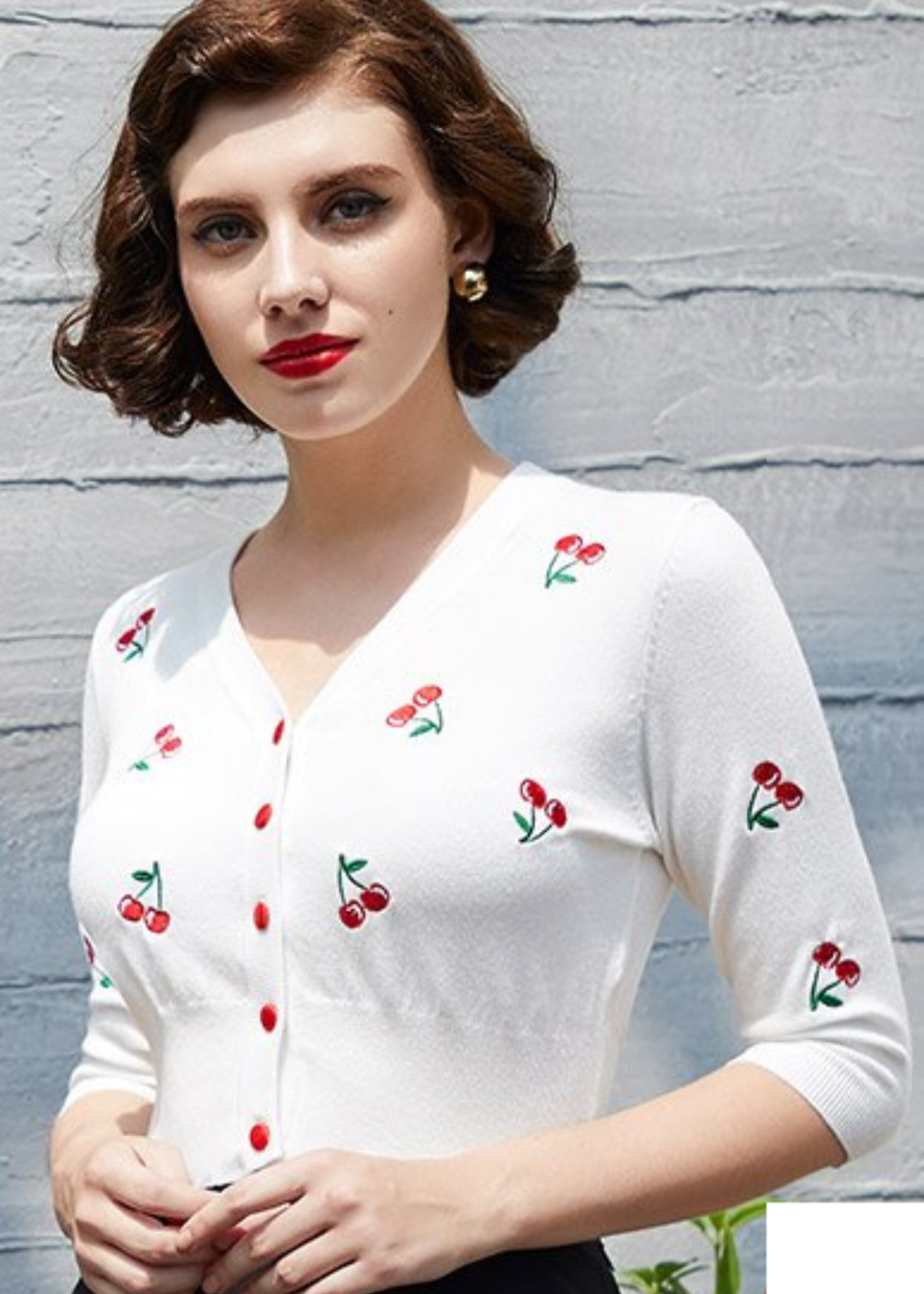 Cropped cherry cardigan with embroidered cherries, worn by a model with vintage-inspired hairstyle and red lips.