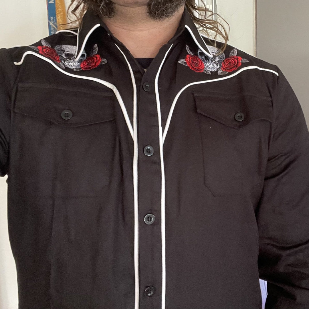 Person wearing a black jacket with white trim and red floral accents indoors.