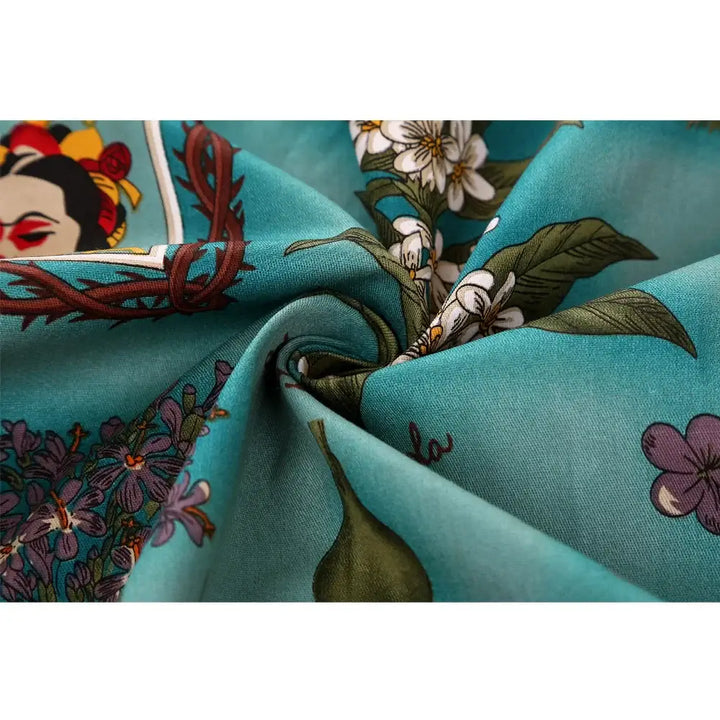Close-up of vibrant fabric featuring Frida Kahlo artwork and floral prints on a teal background.
