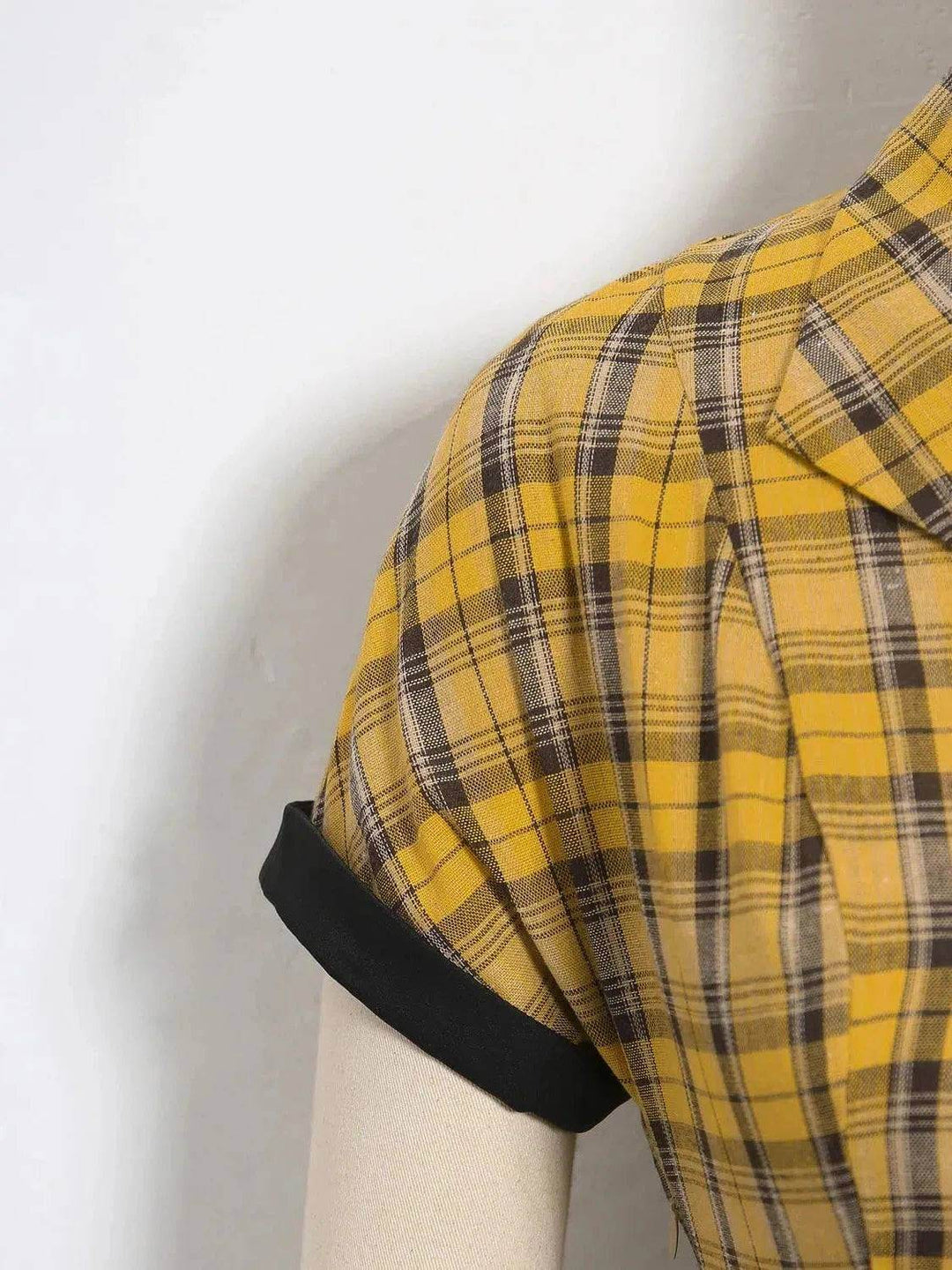 Lucille Plaid Single Breasted 50s Dress showcasing yellow plaid fabric with black cuffed sleeves on a mannequin.