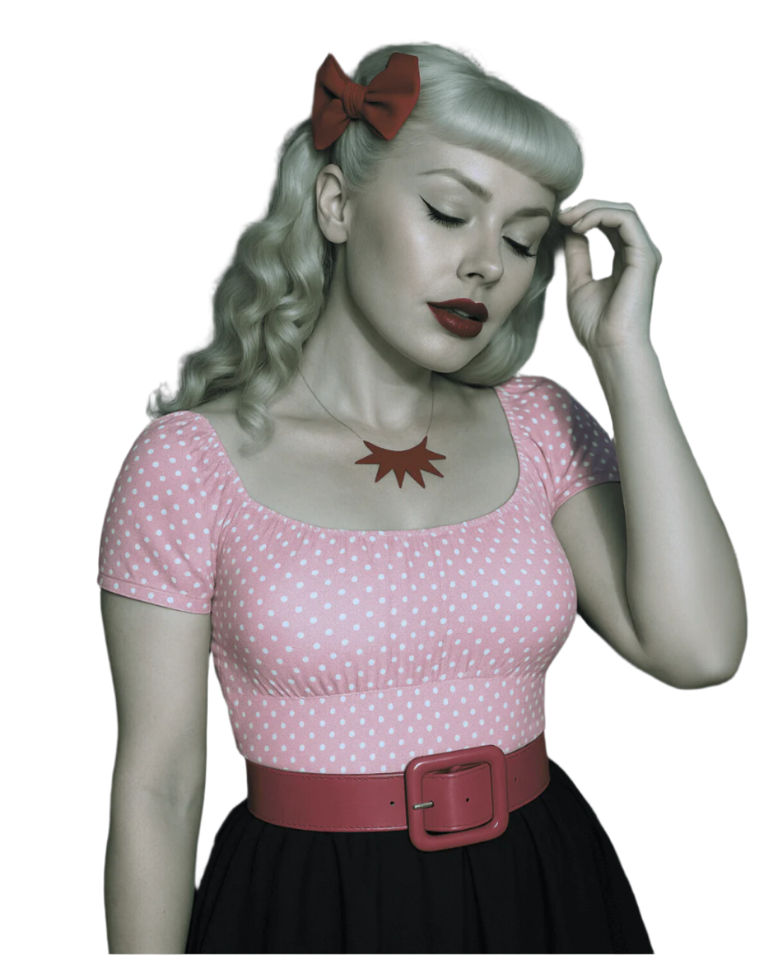 Woman wearing a pink polka dot top with a red belt and a red bow in her hair.