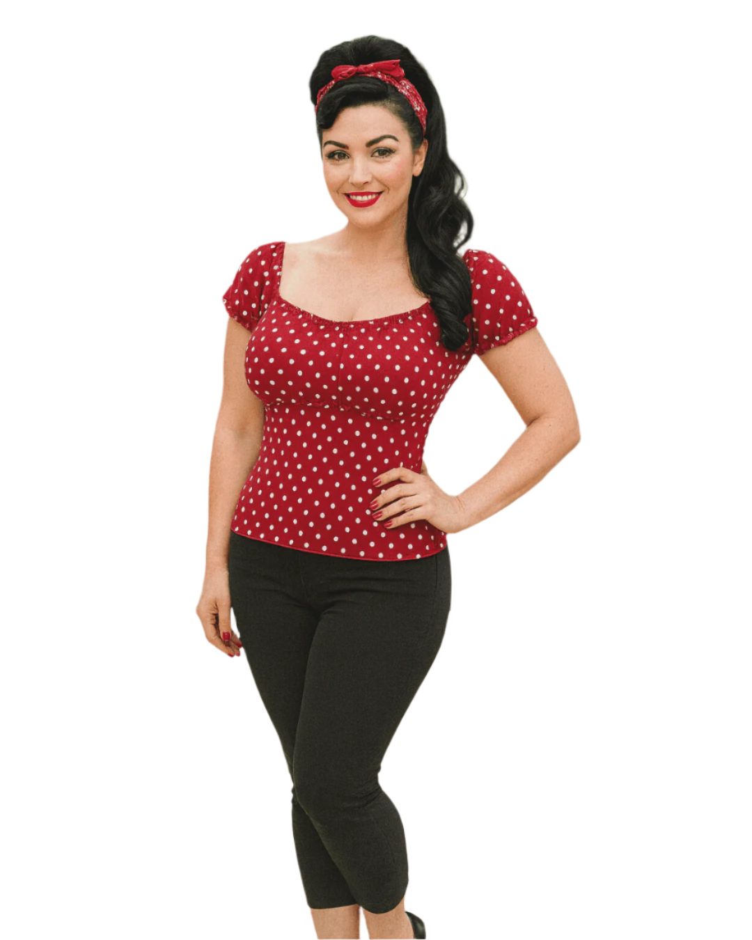 Woman wearing a red polka dot top and black pants on a white background