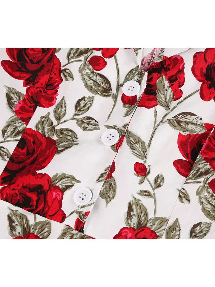 Close-up of vintage dress fabric featuring red roses and green leaves, showcasing buttons and floral pattern.