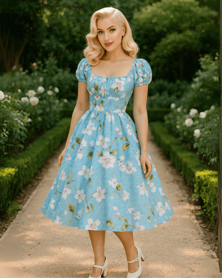 Vintage Peasant Style Blue Floral Dress worn in a garden, featuring puff sleeves and a square neckline.