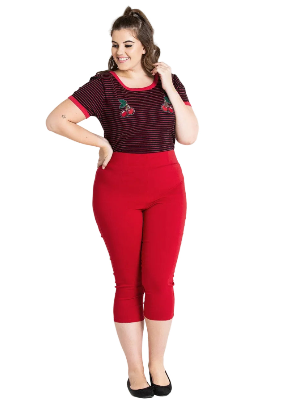 Woman wearing a red and black striped top with cherry design and red capri pants on a white background