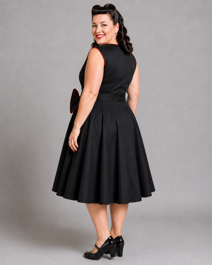 A woman modeling a black sleeveless 1950s-style swing dress with a flared skirt, shown from the back against a plain gray studio background.