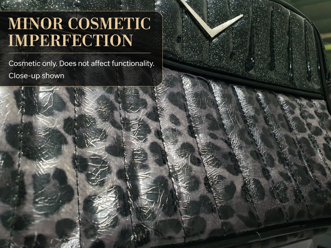 Close-up of a textured leather product, likely a handbag or clutch, featuring a black and gray leopard print on the main body and a black textured leather top section with a silver chevron logo. A text overlay in the top left reads 'MINOR COSMETIC IMPERFECTION' with additional descriptive text below.