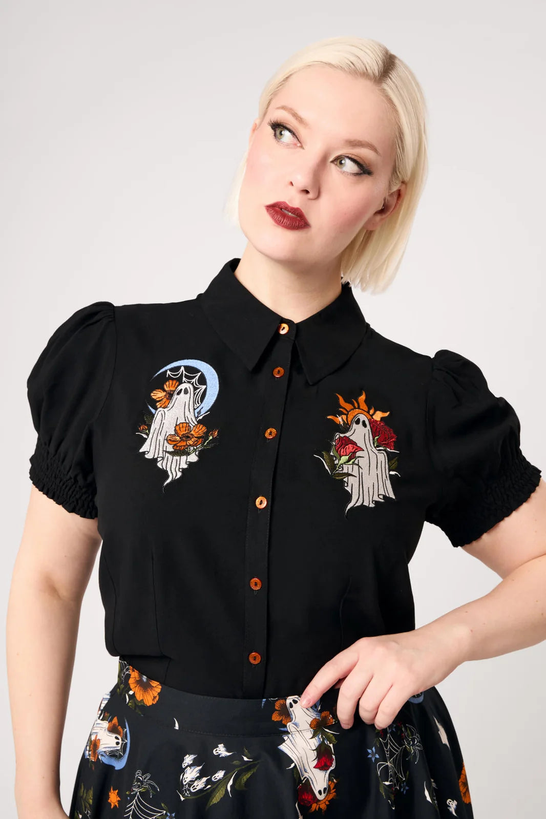 Plus size model wearing Hell Bunny Ghost Flower black ghost embroidered blouse