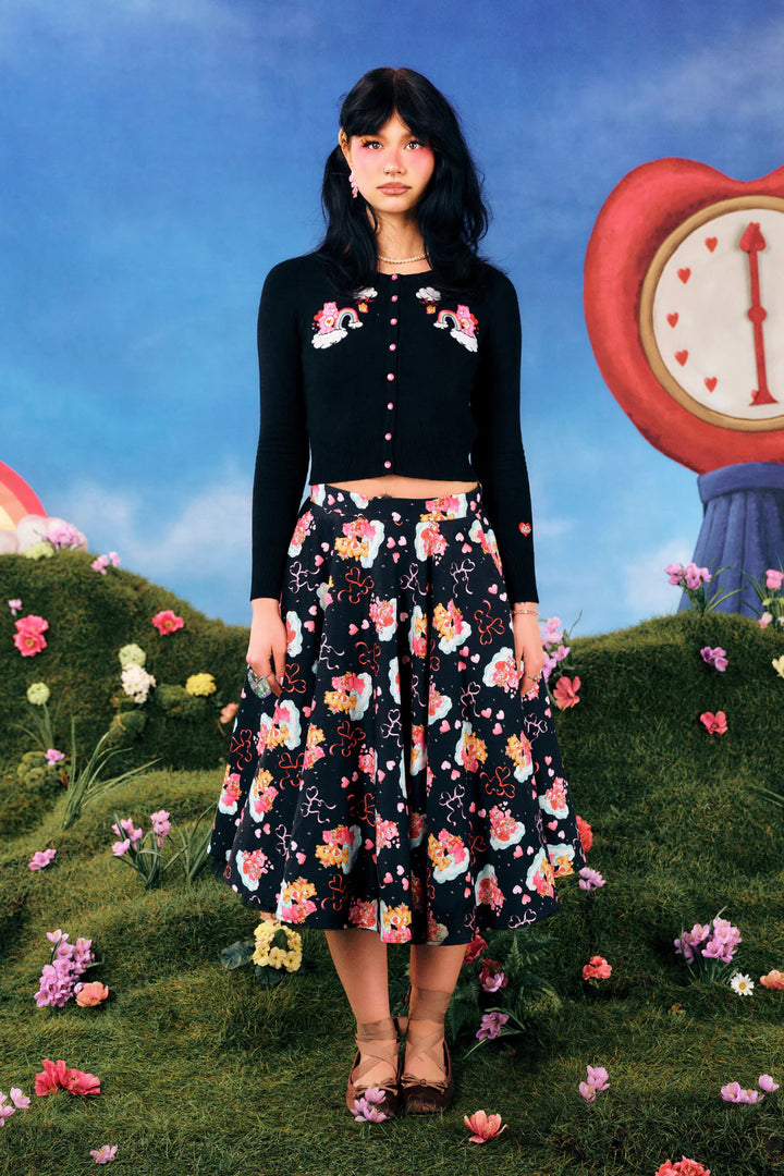 Woman in a floral outfit standing in a whimsical garden with a large clock in the background