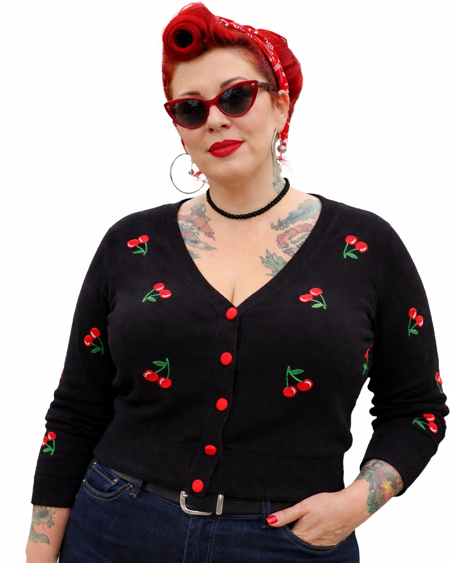 Woman wearing a black cardigan with cherry designs on a white background