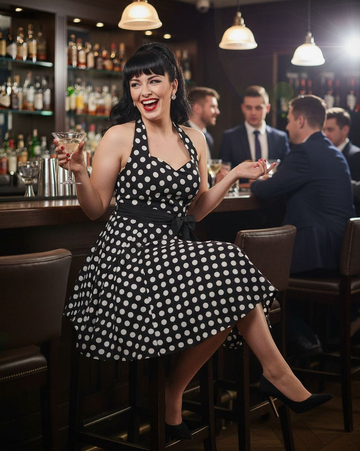 Woman in a polka dot dress sitting at a bar with drinks in hand