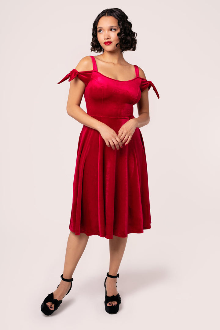 Front view of Hell Bunny Carrie red velvet midi dress with bow shoulder straps on model
