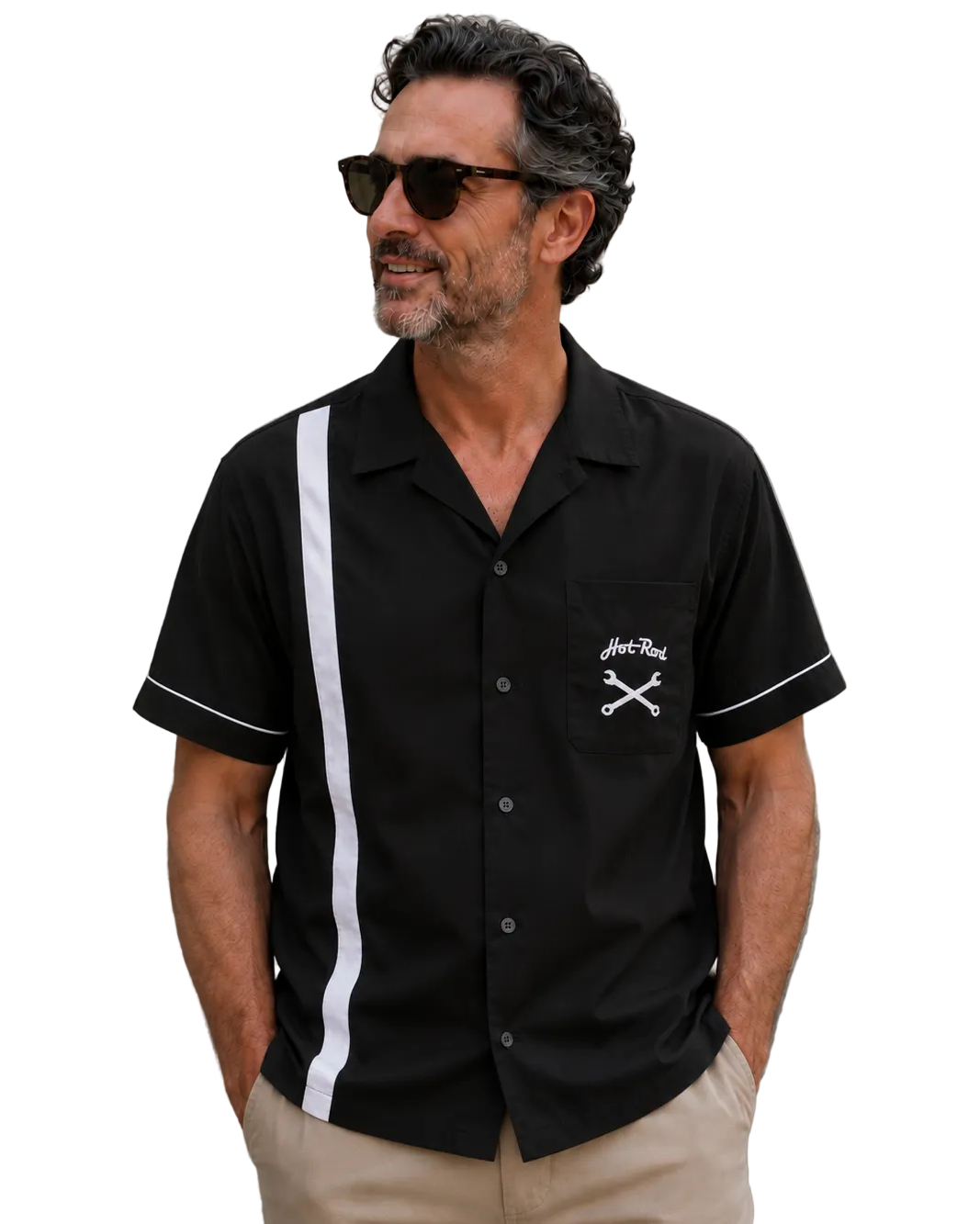 Middle-aged man wearing a black short-sleeve hot rod style bowling shirt with a white vertical stripe, white sleeve piping and chest pocket graphic, standing against a textured concrete wall in beige pants and sunglasses.