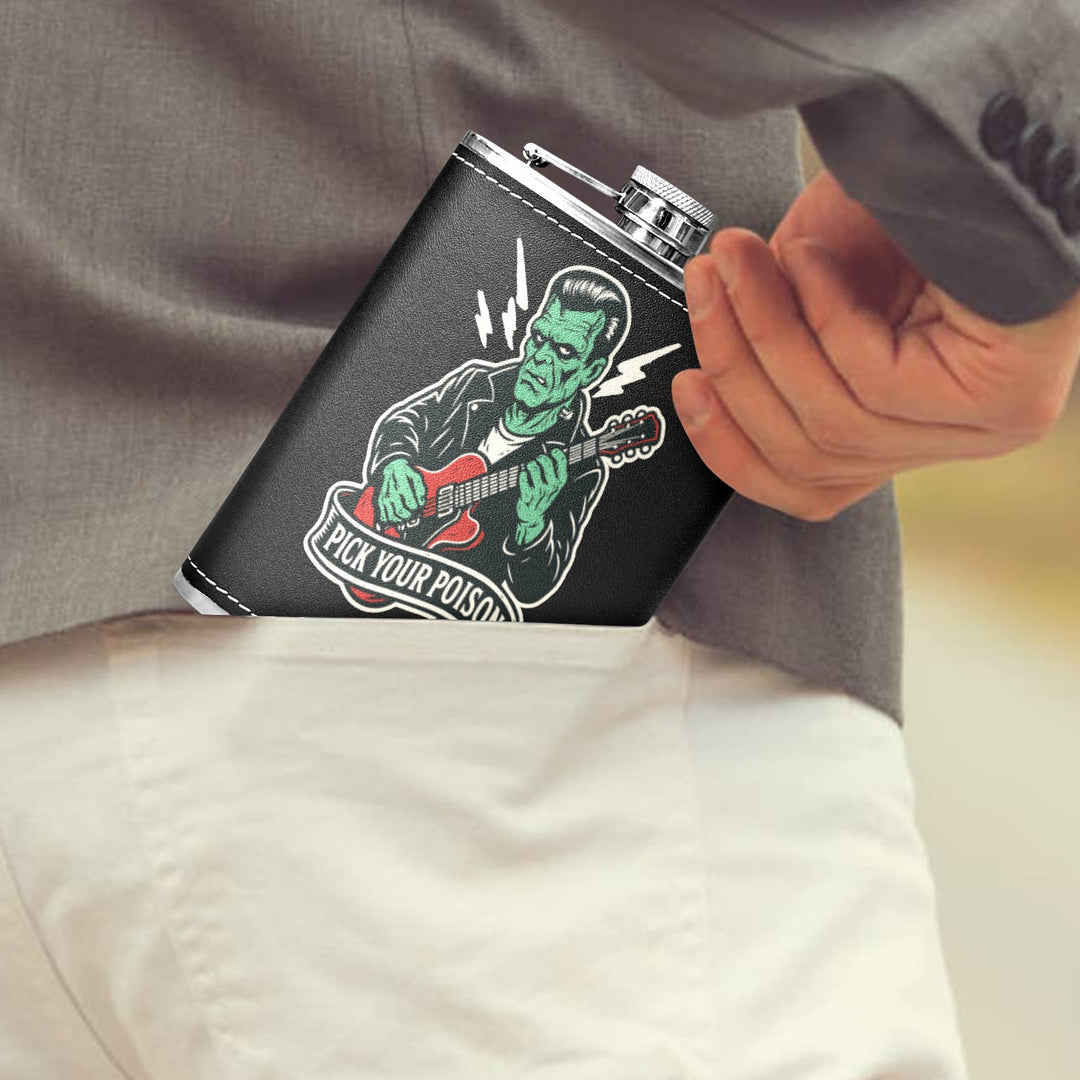 Person placing a black Pick Your Poison 8 oz hip flask featuring a guitar-playing monster into their back pocket.