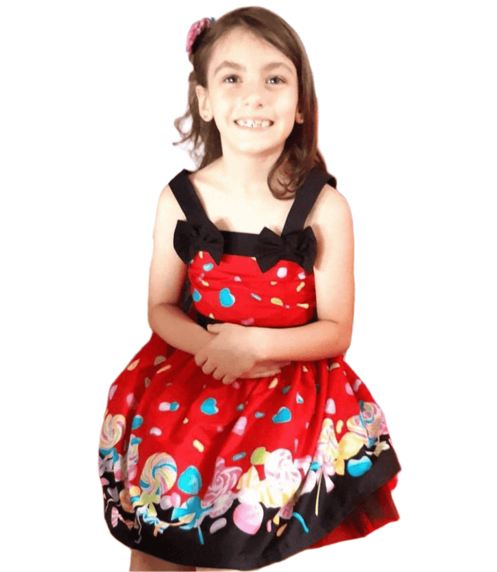 Girl smiling in a bright red Rockabilly dress with candy print, perfect for parties and special occasions.