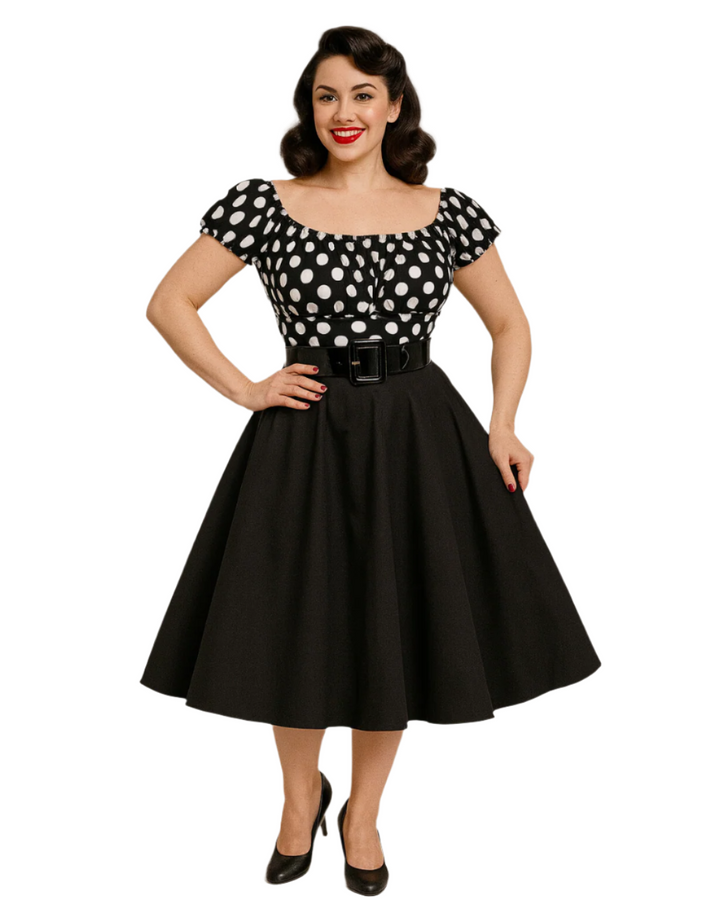 Model showcasing a black and white polka dot peasant top with a belted black skirt and elegant hairstyle.