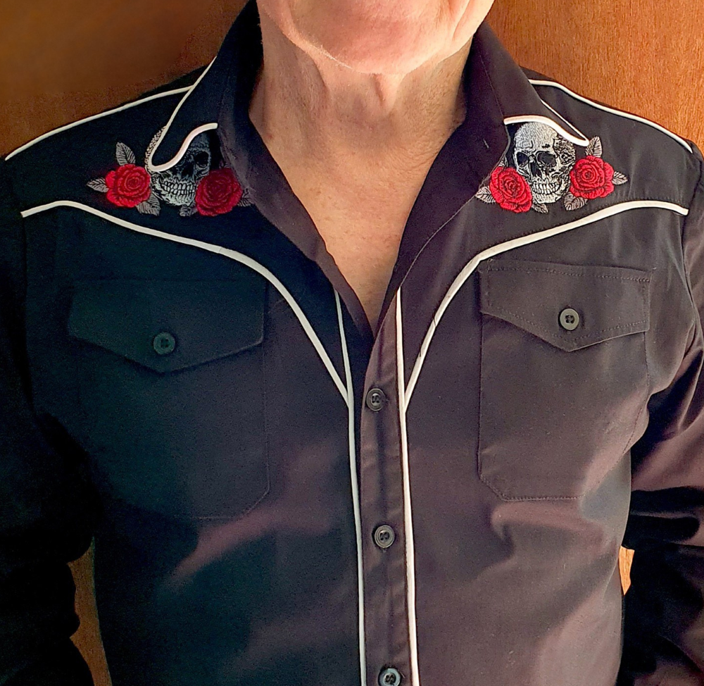 Close-up of a dark shirt with red roses and skull designs on a wooden background