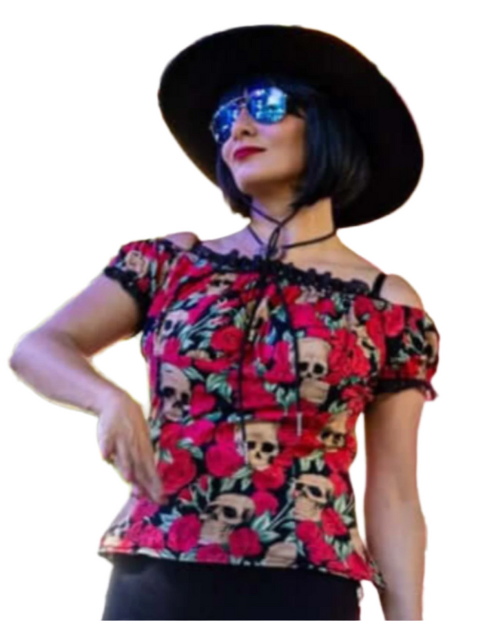 Mezcaltones band member wearing a colorful top with skull and floral pattern, sunglasses, and a black hat outdoors.