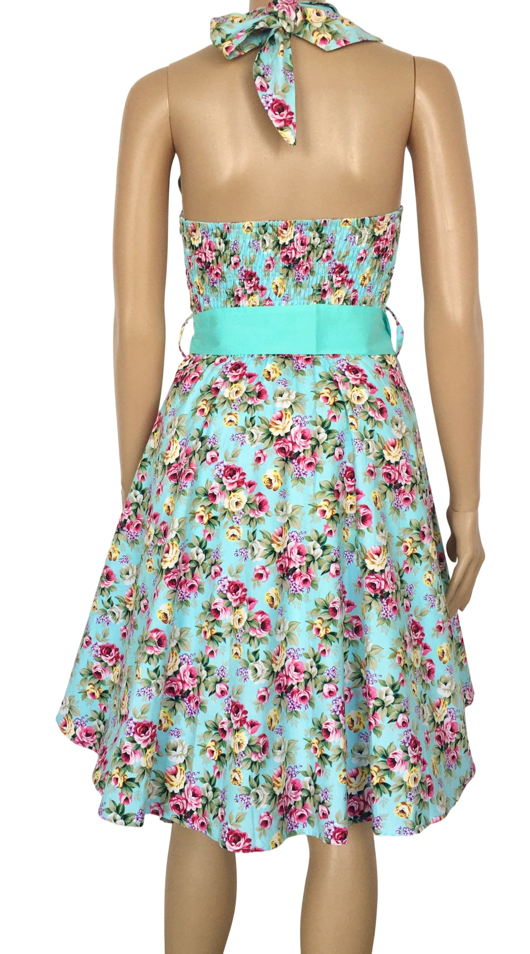 Floral dress with a turquoise belt on a mannequin against a white background