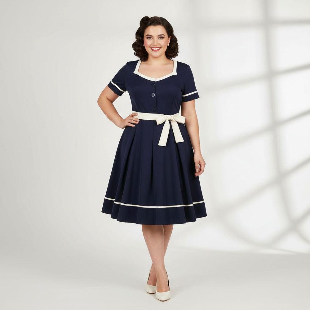 Woman wearing a navy dress with white accents on a white background