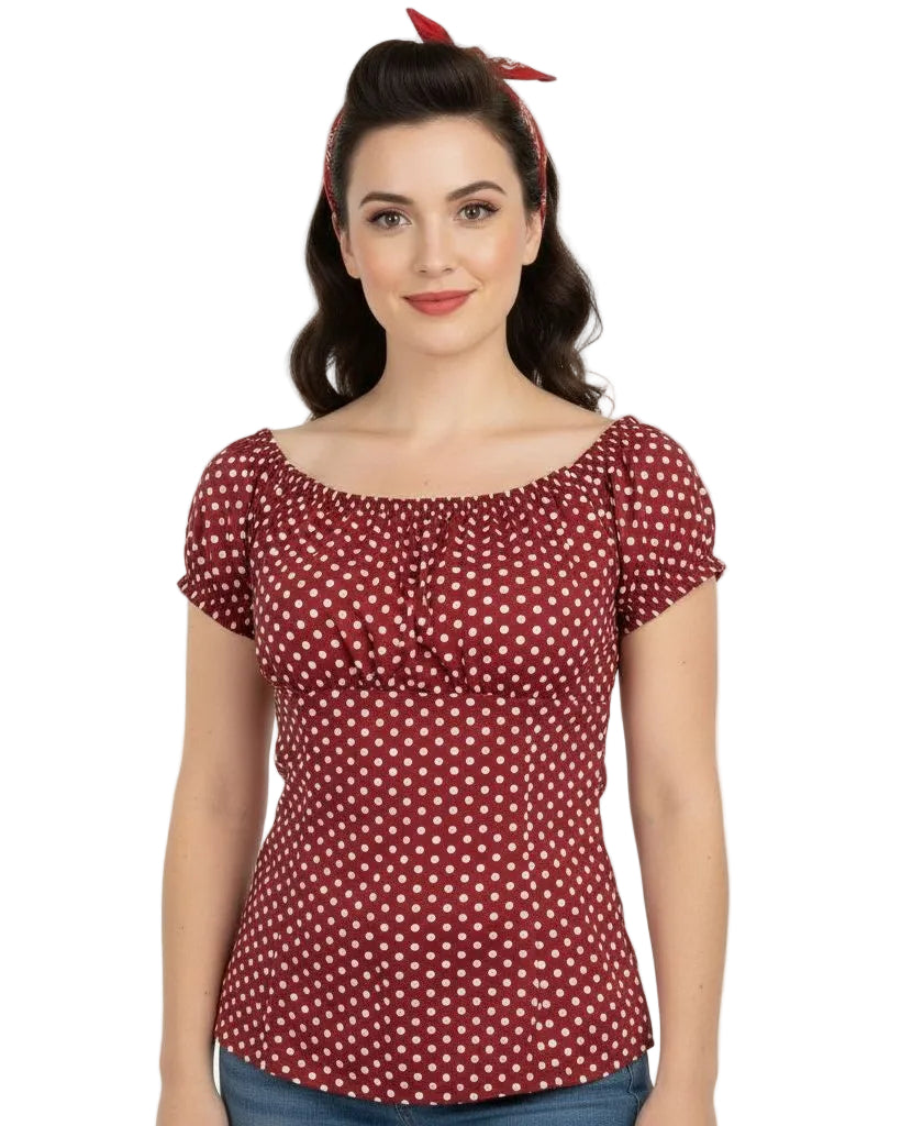 Woman wearing a red polka dot top with a plain background