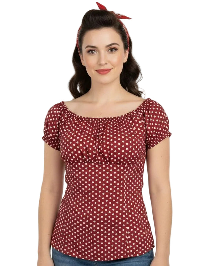 Woman wearing a red polka dot top with a plain background