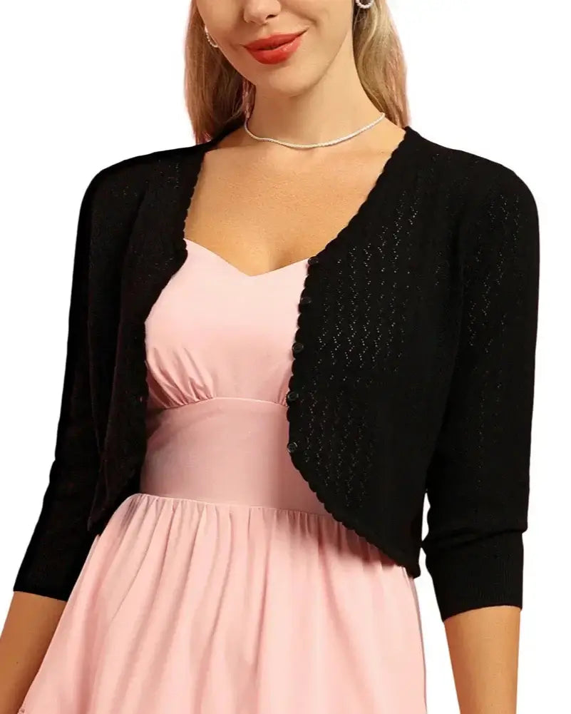 Vintage-inspired black knit bolero shrug with 3/4 sleeves over a pink dress, perfect for autumn and winter outfits.