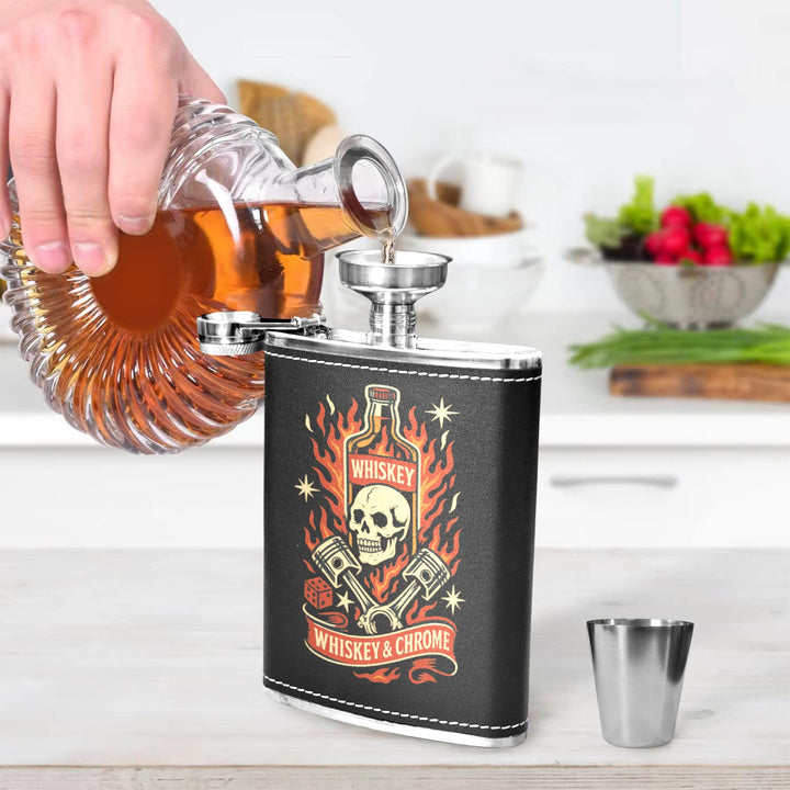 Person pouring whiskey from a bottle into a Whiskey & Chrome 8 oz black hip flask in a stylish kitchen setting.