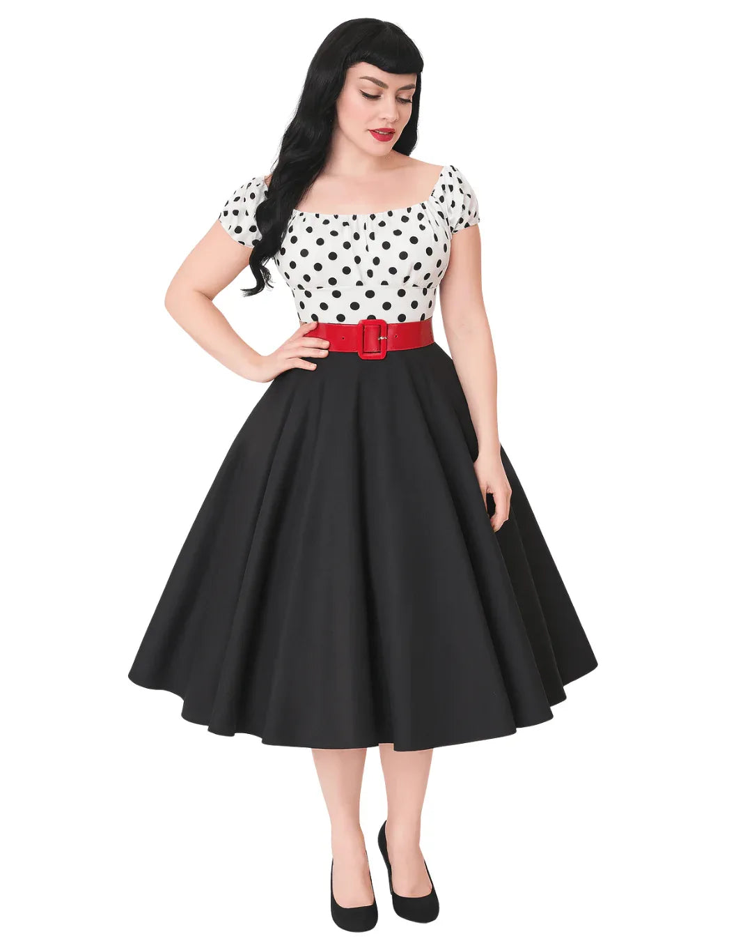 Woman wearing a polka dot top and black skirt with a red belt on a white background
